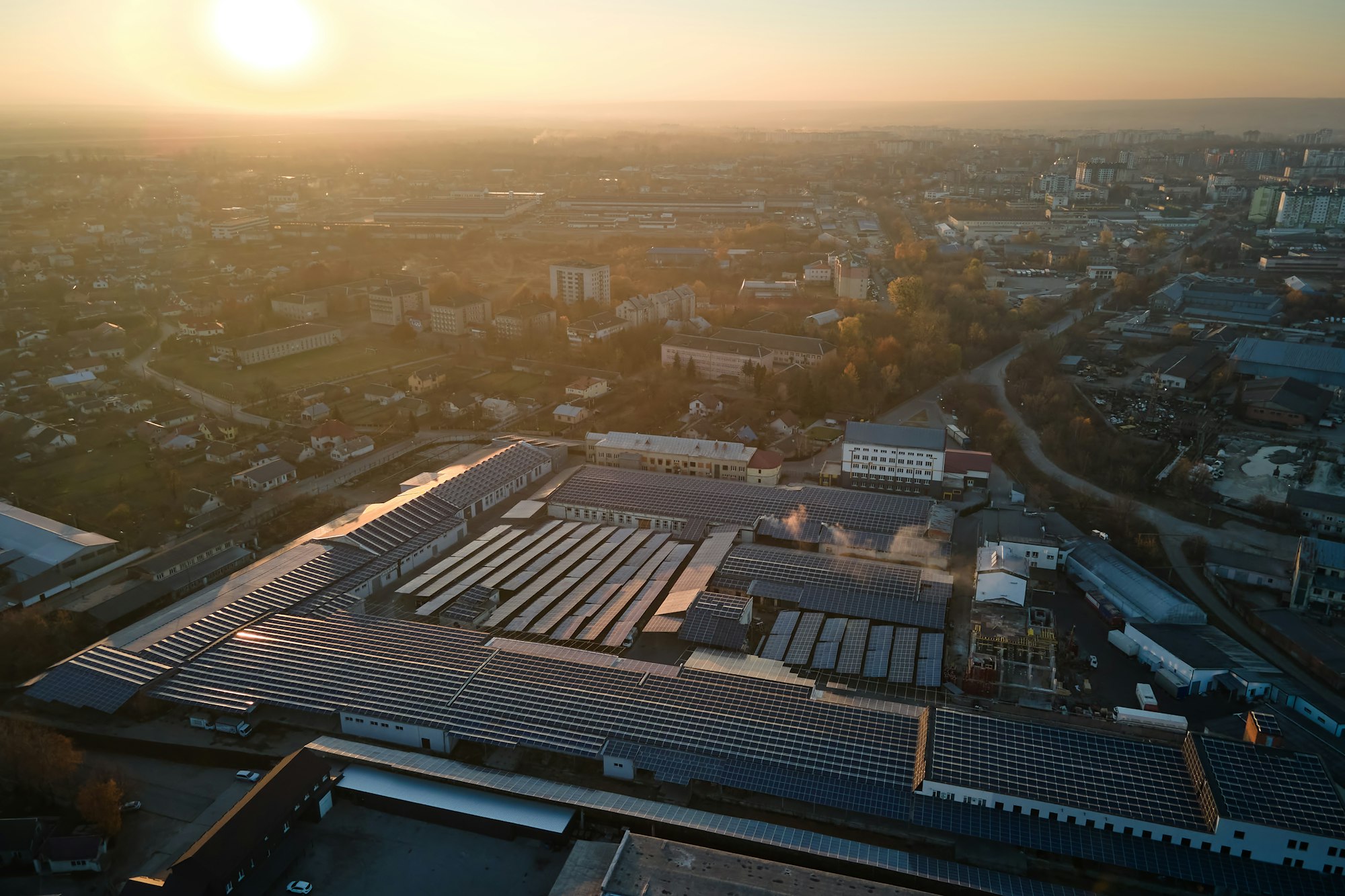 Aerial view of blue photovoltaic solar panels mounted on industrial building roof for producing